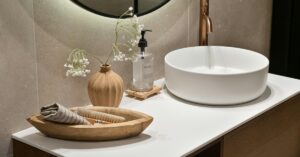 Cena de banheiro moderno com cuba de apoio branca, torneira preta e espelho redondo, destacando o design da cuba e pia para banheiro.