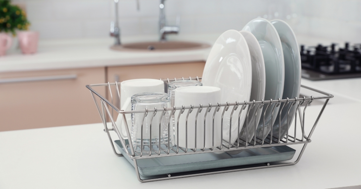 Escorredor de pratos inox sobre a pia, com acabamento escovado e bandeja coletora, destacando organização e secagem rápida na cozinha.