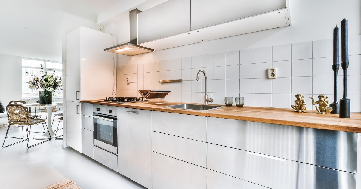 Cozinha planejada para apartamento pequeno moderna com armários verticais, iluminação em LED, eletrodomésticos embutidos e bancada de quartzo clean.