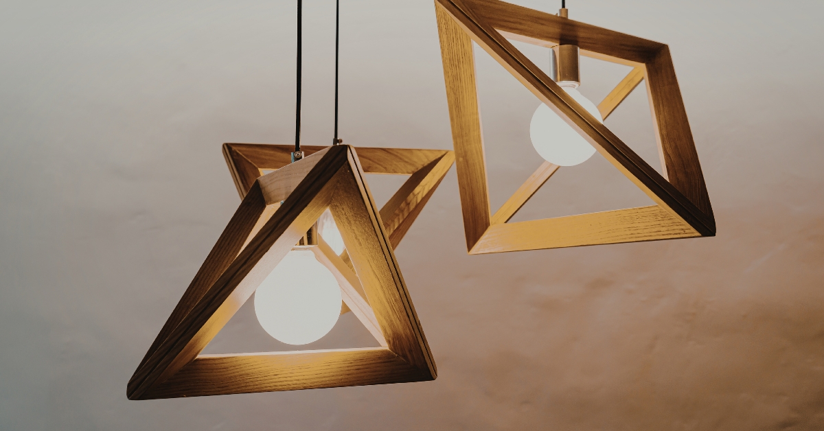 Cozinha de alto padrão decorada com uma sofisticada luminaria pendente para cozinha de design curvo e dourado instalada sobre a ilha central.