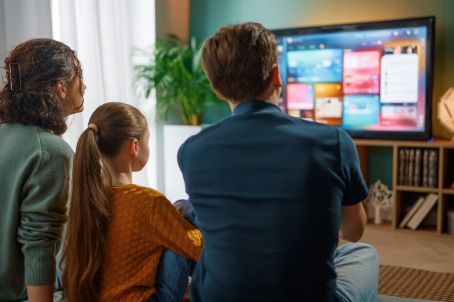 Sala decorada moderna exibindo um elegante painel de tv planejado para sala pequena em madeira clara com iluminação LED e uma TV HQ 60 Polegadas instalada.