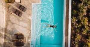 Área de lazer luxuosa exibindo uma piscina com borda infinita de água cristalina tratada com os melhores produtos para limpar piscina de 2026.