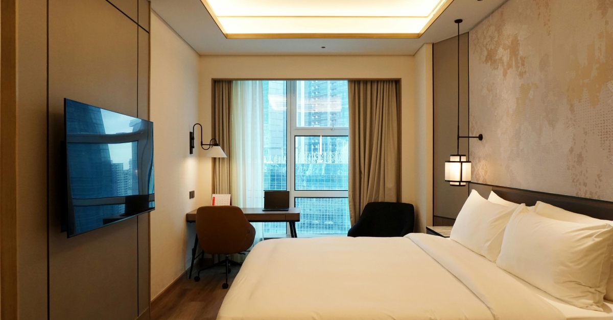 Quarto aconchegante com TV no quarto fixada na parede e iluminação suave, integrando design moderno e decoração em quarto pequeno.